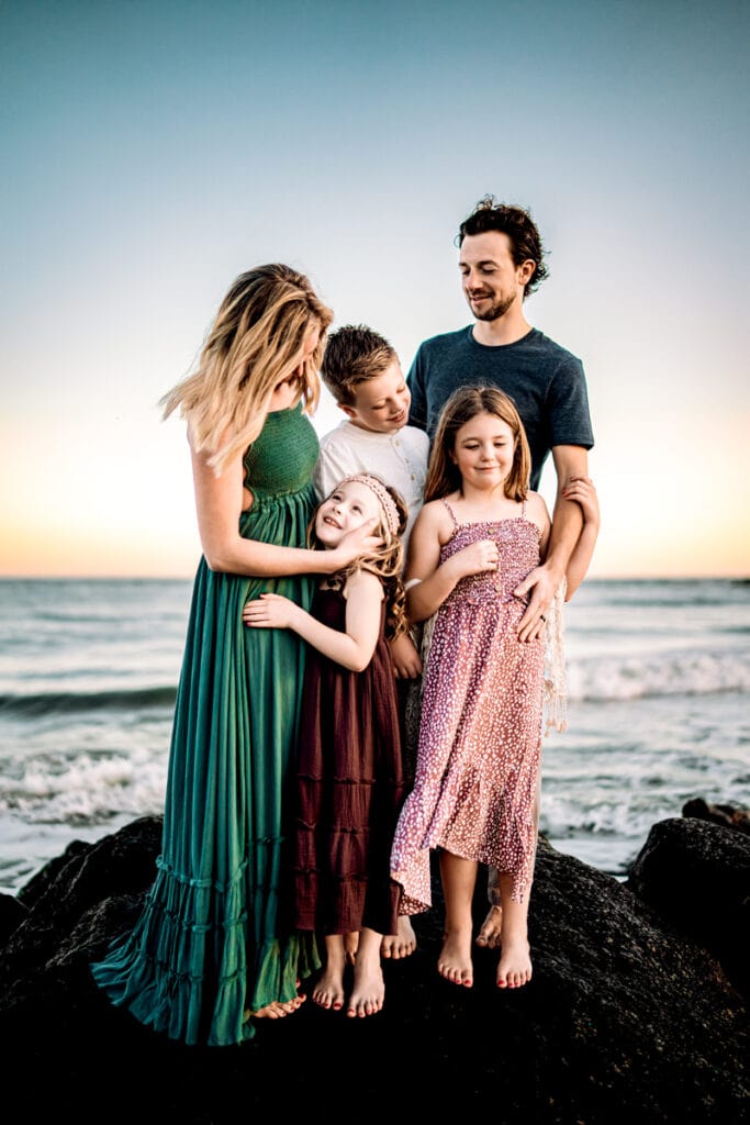 Family Photographer, a mother and father stand with their two sons and daughter near the ocean